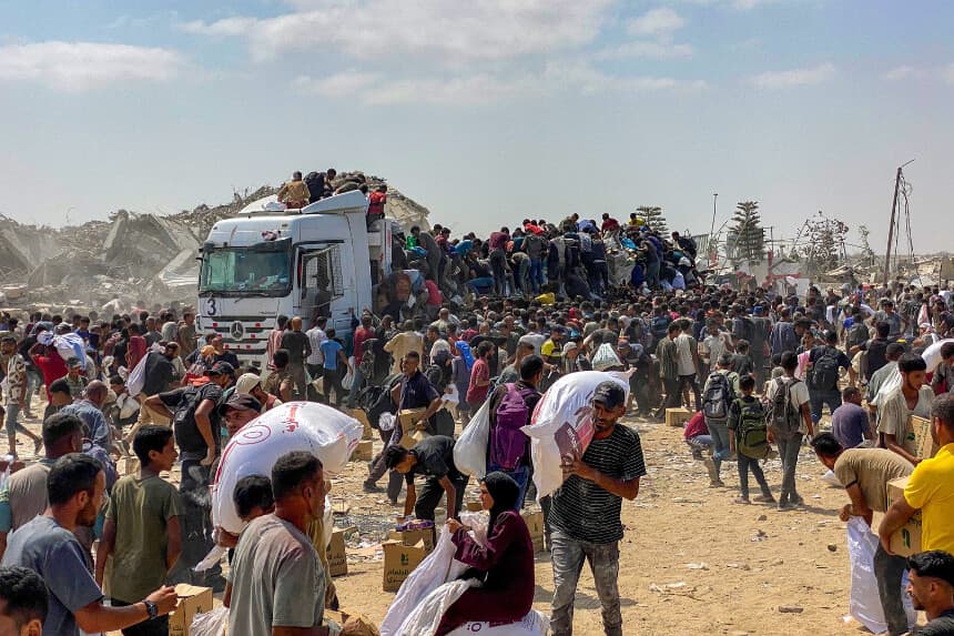 Residentes desplazados de Gaza transportan paquetes de alimentos mientras asaltan camiones que transportan ayuda humanitaria en Khan Yunis, en el sur de la Franja de Gaza, el 9 de agosto de 2025. (AFP vía Getty).