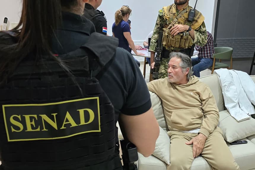 Fotografía cedida por la Secretaría Nacional Antidrogas que muestra a integrantes de las Fuerzas Armadas custodiando al presunto líder del grupo criminal La Barredora, Hernán Bermúdez Requena, este sábado en Mariano Roque Alonso, Paraguay. (EFE/ Secretaría Nacional Antidrogas de Paraguay)