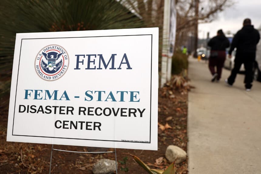 La gente pasa junto a un cartel de la FEMA tras una rueda de prensa en el Centro de Recuperación de Desastres de Altadena, en Altadena (California), tras el incendio de Eaton el 30 de enero de 2025. (Mario Tama/Getty Images).