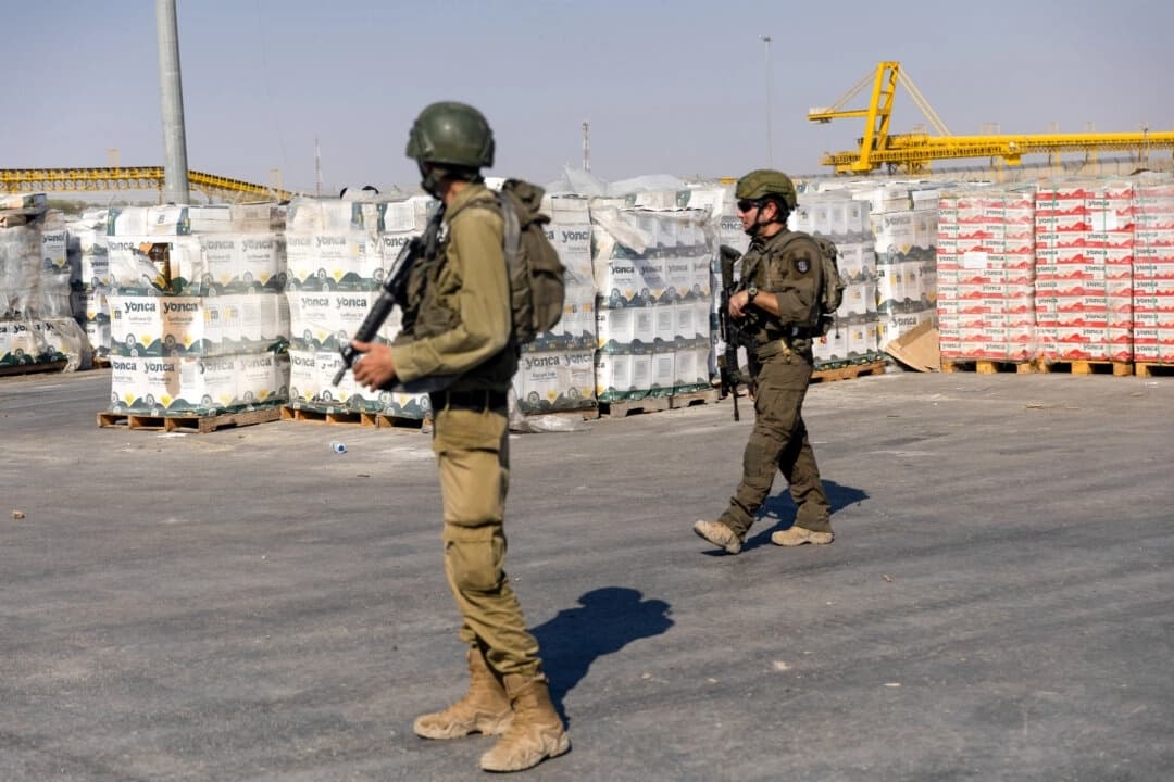 Soldados israelíes pasan junto a paquetes de ayuda humanitaria que esperan ser recogidos en el lado palestino del paso fronterizo de Kerem Shalom, en la Franja de Gaza, el 24 de julio de 2025. (Amir Levy/Getty Images)