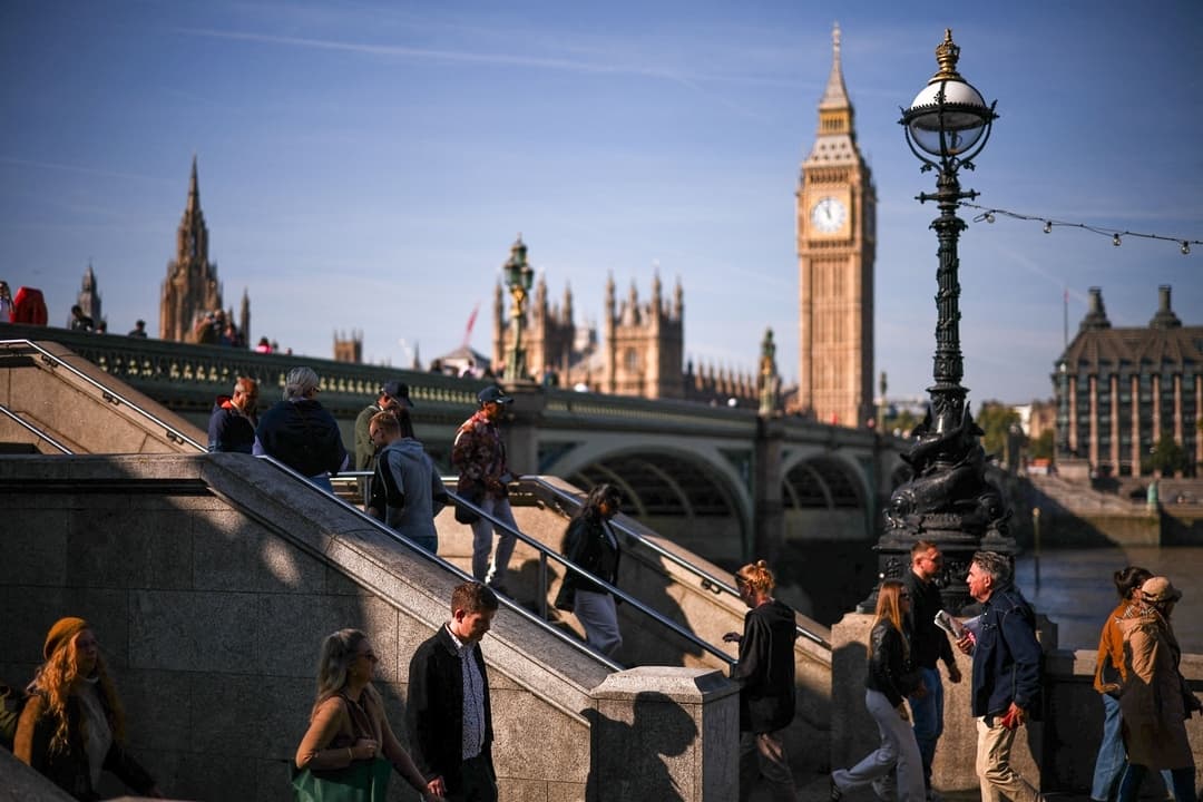 Peatones caminan por la orilla sur del Támesis, con la Torre Isabel y el Parlamento al fondo, en Londres, el 29 de septiembre de 2025. (Henry Nicholls/AFP vía Getty Images)