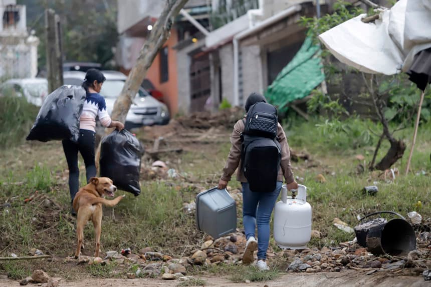 Personas caminan con sus pertenencias en una zona afectada por las fuertes lluvias en Huauchinango, México. (EFE/ Hilda Ríos)