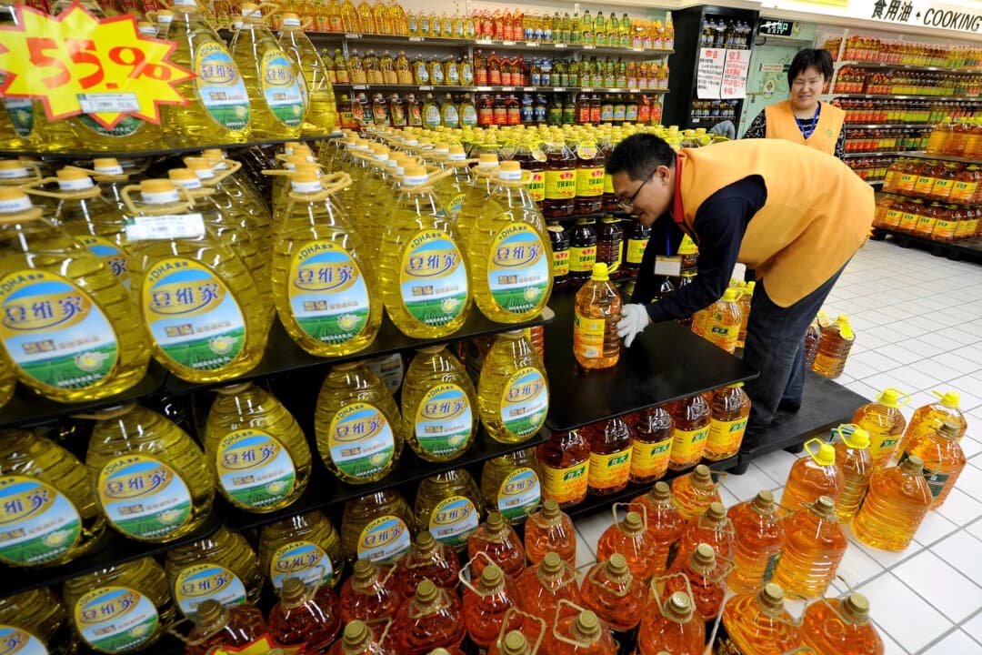 En esta foto de archivo, trabajadores chinos colocan botellas de aceite de cocina en un supermercado de Hefei, provincia de Anhui, China. (STR/AFP/Getty Images)