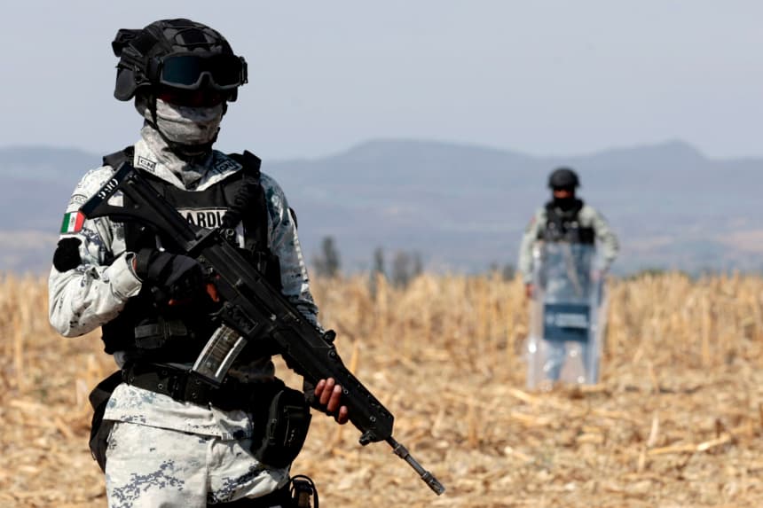 Oficiales de la Guardia Nacional vigilan mientras personal de la Fiscalía General de México trabaja en un segundo supuesto centro de reclutamiento de crimen organizado ubicado por la Guardia Nacional en la comunidad de La Vega, en el municipio de Tehuchitlán, estado de Jalisco, México, el 24 de marzo de 2025. (ULISES RUIZ/AFP via Getty) Images)