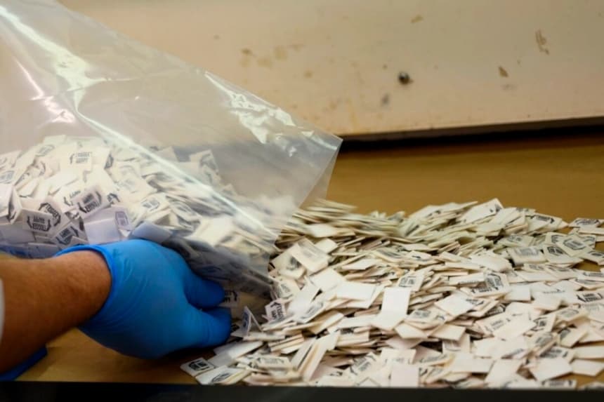Un experto de la Administración para el Control de Drogas (DEA) vierte 2500 paquetes de fentanilo confirmado sobre una superficie para su análisis en el Laboratorio Regional Noreste de la DEA en la ciudad de Nueva York, el 8 de octubre de 2019. (Don Emmert/AFP vía Getty Images)