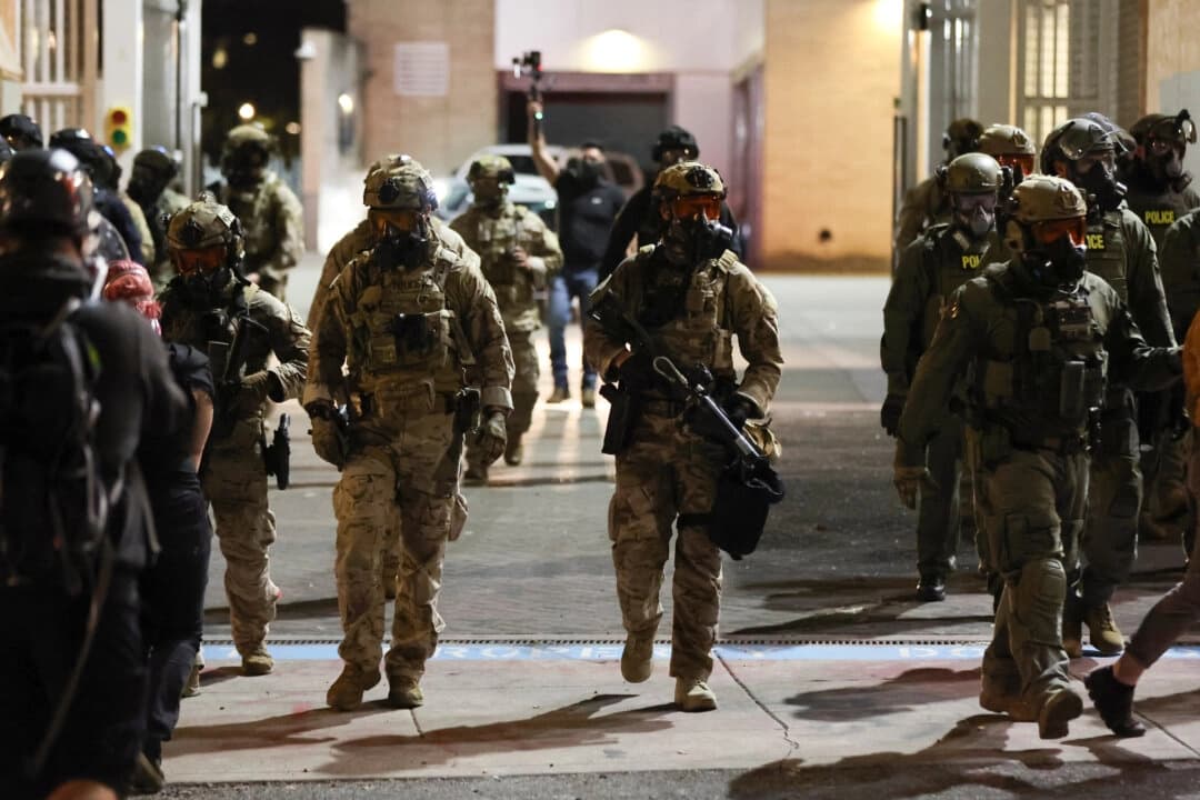 Agentes federales se desplazan en una calle mientras la gente protesta frente a una instalación del Servicio de Inmigración y Control de Aduanas de Estados Unidos en Portland, Oregón, el 3 de octubre de 2025. (Foto: Amanda Loman/AP)