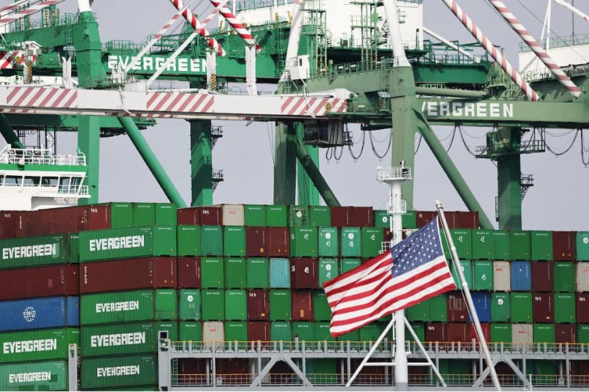 Una bandera estadounidense ondea cerca de contenedores apilados en un buque portacontenedores de Evergreen en el puerto de Los Ángeles el 26 de septiembre de 2025 en Los Ángeles, California. (Mario Tama/Getty Images)