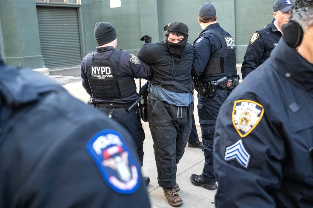 Una persona es detenida por el Departamento de Policía de Nueva York mientras activistas de inmigración bloquean un garaje utilizado por camionetas de ICE durante una protesta contra una supuesta operación de ICE en Canal Street en la ciudad de Nueva York, el 29 de noviembre de 2025. (Stephanie Keith/Getty Images)
