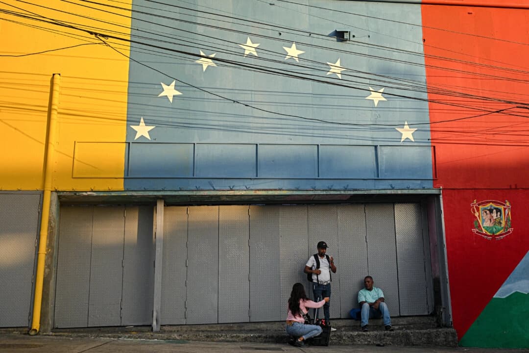 Personas conversan frente a un mural con los colores de la bandera nacional venezolana en Caracas el 12 de septiembre de 2025. (Federico Parra/AFP vía Getty Images)