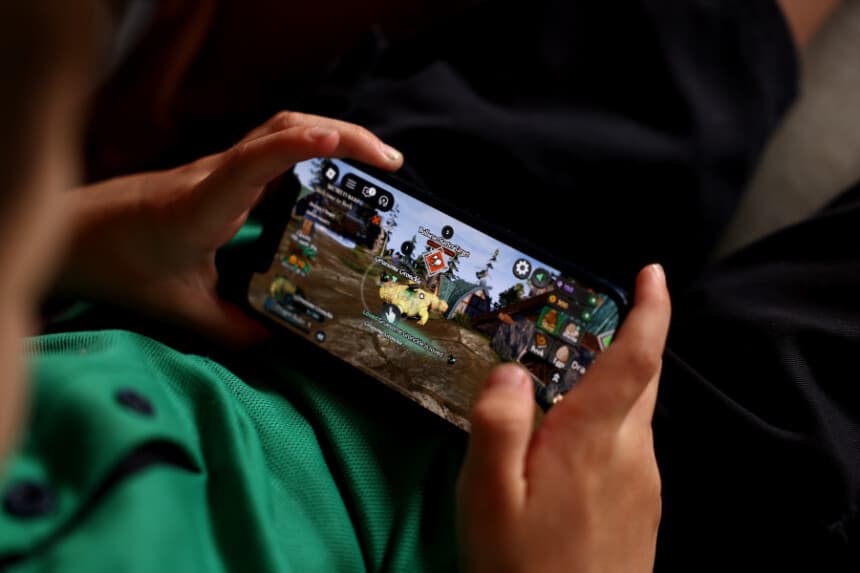En esta ilustración fotográfica, unos niños pequeños sostienen un iPhone mientras utilizan la plataforma de juegos online Roblox el 19 de noviembre de 2025 en Auckland, Nueva Zelanda. (Ilustración fotográfica de Getty Images)