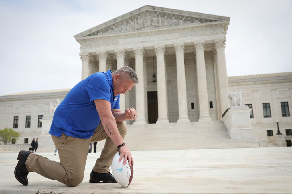 El ex entrenador asistente de fútbol americano de la escuela secundaria Bremerton High School, Joe Kennedy, se arrodilla frente al Tribunal Supremo de los Estados Unidos después de que su caso judicial, Kennedy contra el distrito escolar de Bremerton, fuera debatido ante el tribunal el 25 de abril de 2022 en Washington, D.C. Kennedy fue despedido de su trabajo por los funcionarios de la escuela pública de Bremerton en 2015 tras negarse a dejar de rezar en el campo después de los partidos de fútbol americano. (Foto de Win McNamee/Getty Images)