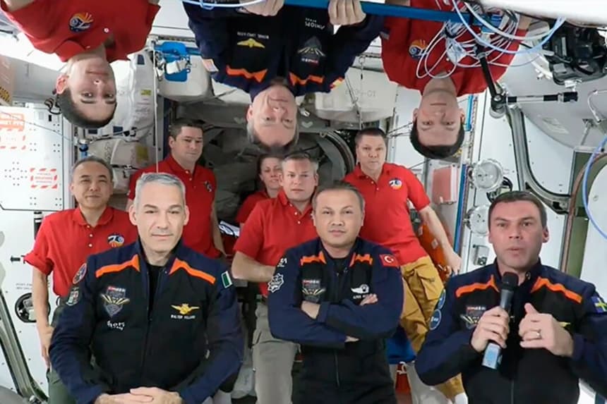 En esta imagen de un video, los 11 miembros de la tripulación de la Estación Espacial Internacional que representan a las tripulaciones de la Expedición 70 (camisetas rojas) y Axiom Space 3 (trajes azul oscuro) se reúnen para una ceremonia de despedida llamando a los controladores de la misión en la Tierra, el 2 de febrero de 2024. (NASA vía AP)