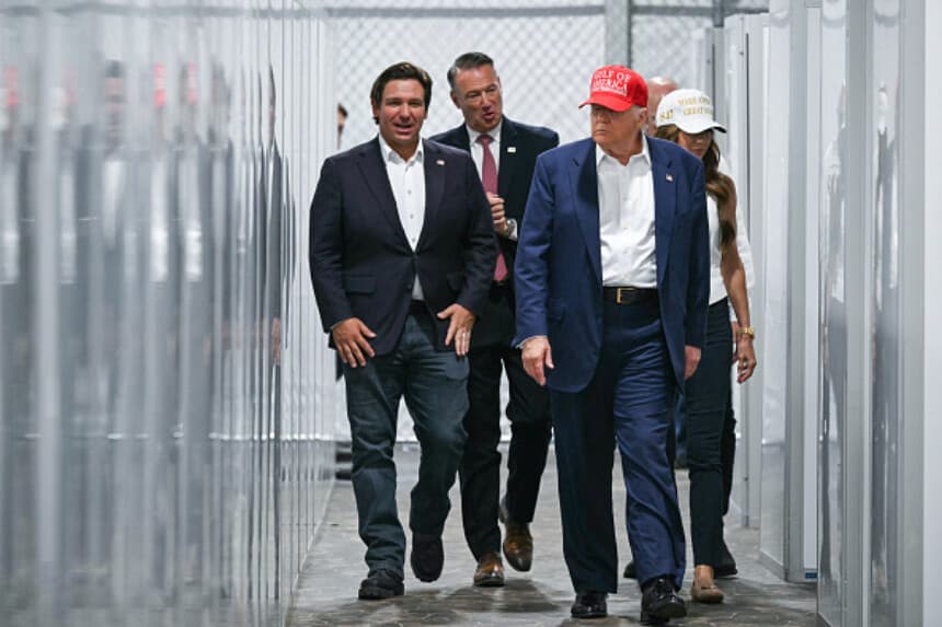 El presidente de los Estados Unidos, Donald Trump (segundo por la derecha), el gobernador de Florida, Ron DeSantis (izquierda), y la secretaria de Seguridad Nacional, Kristi Noem (derecha), recorren una sección de instalaciones médicas durante su visita a un centro de detención de migrantes, apodado "Alligator Alcatraz", ubicado en el aeropuerto de entrenamiento y transición Dade-Collier en Ochopee, Florida, el 1 de julio de 2025. (ANDREW CABALLERO-REYNOLDS/AFP vía Getty Images).