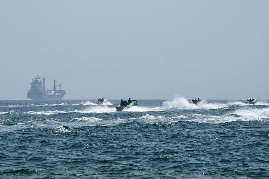 Pequeñas embarcaciones cargadas de mercancías navegan junto al buque portacontenedores Marsa Victory, con bandera de San Cristóbal y Nieves, en las aguas del estrecho de Ormuz, frente a la costa de Khasab, en la península de Musandam, al norte de Omán, el 25 de junio de 2025. (GIUSEPPE CACACE/AFP a través de Getty Images)
