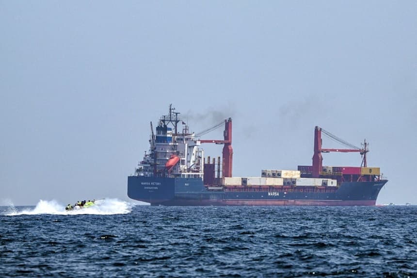 Una embarcación se aproxima al buque portacontenedores Marsa Victory, con bandera de San Cristóbal y Nieves, mientras navega por las aguas del estrecho de Ormuz, frente a la costa de Khasab, en la península de Musandam, al norte de Omán, el 25 de junio de 2025. (Giuseppe Cacace/AFP)