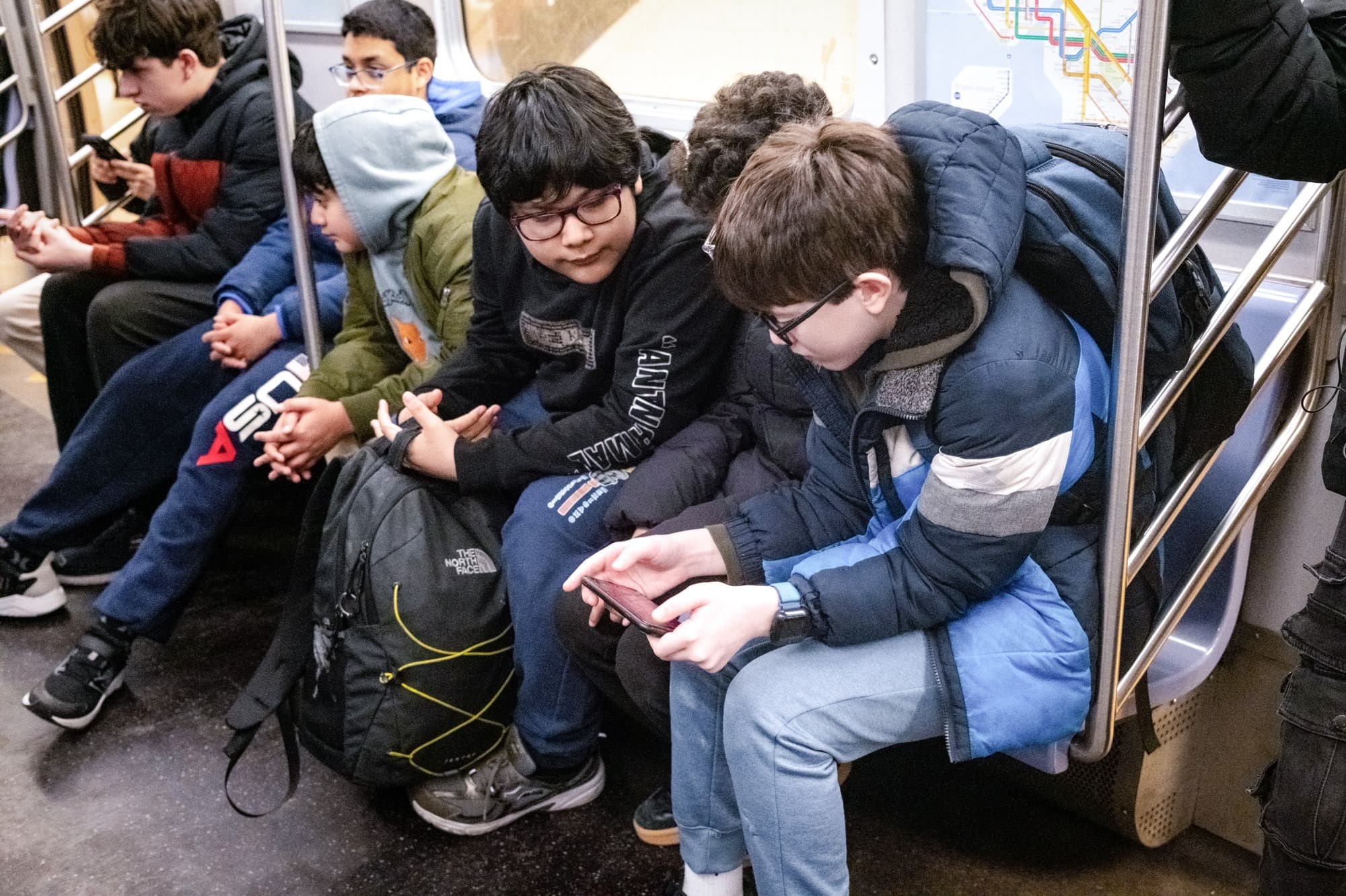 Unos jóvenes miran un teléfono en el metro de la ciudad de Nueva York el 26 de marzo de 2026. (Samira Bouaou/The Epoch Times).