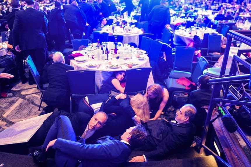Los invitados se refugian tras un tiroteo en el hotel Hilton, donde se celebró la cena anual de la Asociación de Corresponsales de la Casa Blanca en Washington el 25 de abril de 2026. Según los informes, el presidente Donald Trump y otros funcionarios del gobierno fueron evacuados del hotel. (Nathan Howard/Getty Images)
