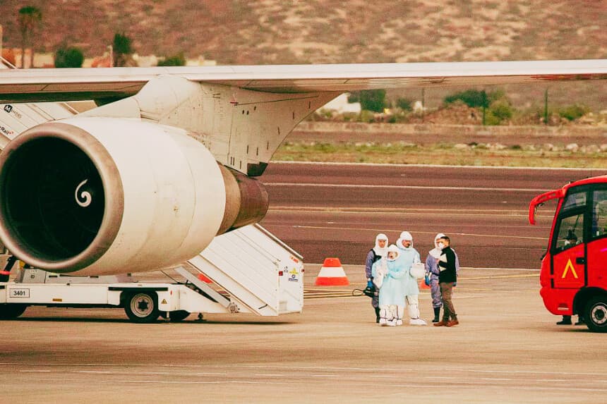 Se ve a personas con trajes de protección mientras los pasajeros suben a un avión con destino a EE. UU. que transporta a los pasajeros evacuados del crucero MV Hondius, de bandera holandesa y afectado por el hantavirus, en el aeropuerto de Tenerife Sur-Reina Sofía, en la isla de Tenerife, en las Islas Canarias, España, el 10 de mayo de 2026. (Antonio Sempere / AFP vía Getty Images)
