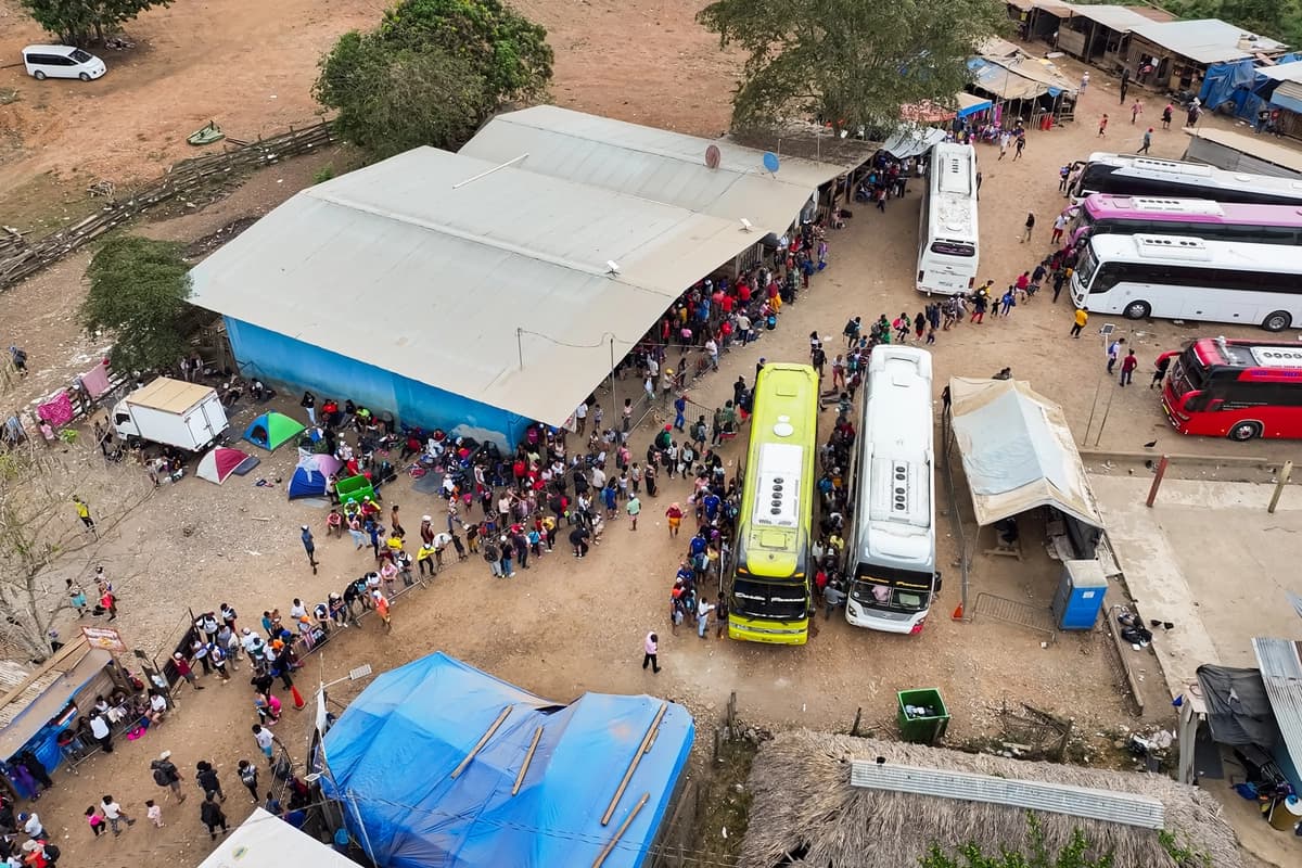 Inmigrantes ilegales que cruzaron el Tapón del Darién desde Colombia hacia Panamá esperan en fila para tomar autobuses hacia Costa Rica, en el campamento de migrantes de Lajas Blancas en Darién, Panamá, el 10 de julio de 2024. (The Epoch Times)