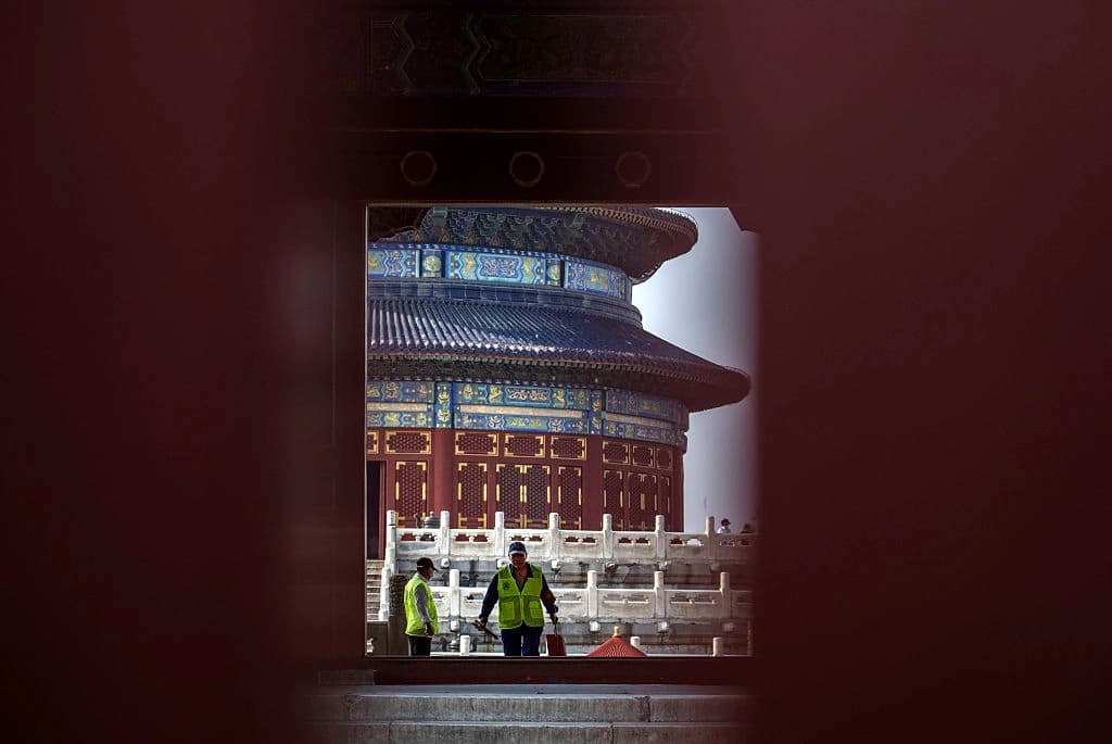 Trabajadores se muestran a través de la rendija de las puertas cerradas del Salón de Oración por las Buenas Cosechas en el Templo del Cielo en Beijing, China, el 12 de mayo de 2026. (Kevin Frayer/Getty Images)