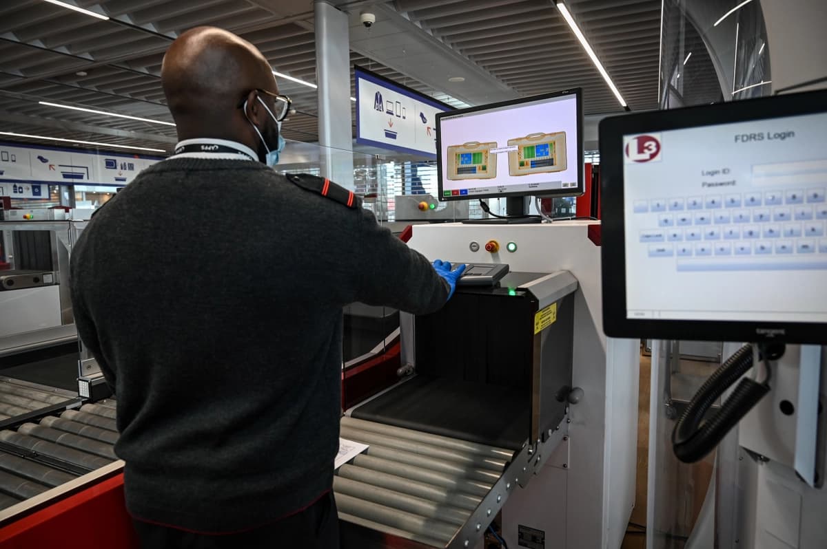 Un miembro del personal del aeropuerto revisa el equipaje de los pasajeros que pasa por la máquina de rayos X en la Terminal 3 del aeropuerto de Orly, en las afueras de París, el 22 de junio de 2020. (BERTRAND GUAY/AFP vía Getty Images)