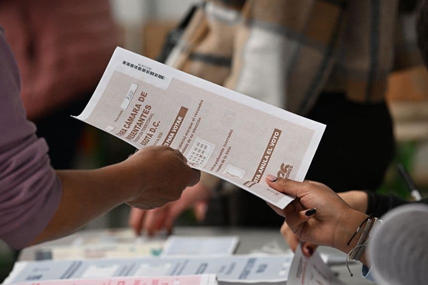 Una mujer recibe su boleta electoral antes de votar en un centro de votación durante las elecciones legislativas celebradas en Bogotá, el 8 de marzo de 2026. (Raúl ARBOLEDA / AFP vía Getty Images)