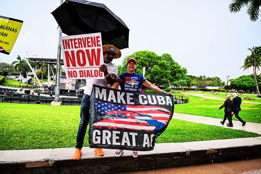 La gente sostiene pancartas y carteles bajo la lluvia durante una manifestación por una «Cuba libre» en Miami, Florida, el 26 de abril de 2026, para pedir la salida de los Castro y del Partido Comunista del poder en Cuba. (CHANDAN KHANNA / AFP vía Getty Images)