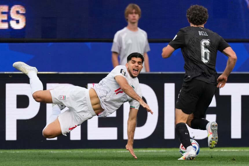 El iraní Arya Yousefi cae al suelo mientras el neozelandés Joe Bell disputa el balón durante el partido de la Copa Mundial de Fútbol entre ambos países en Inglewood, California, el 15 de junio de 2026. (Mark J. Terrill/AP).