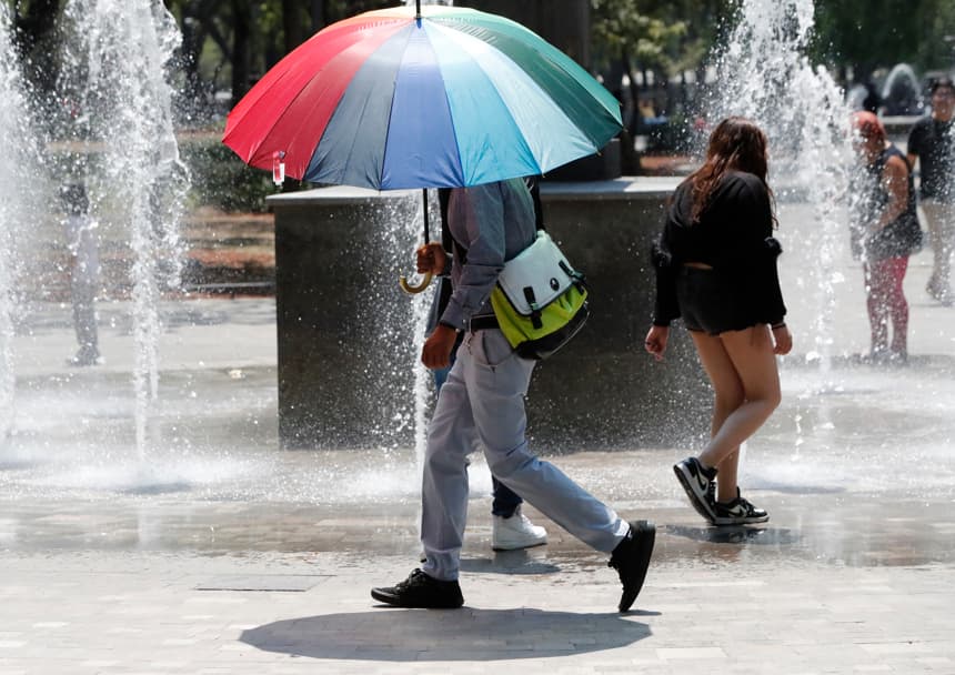Una persona utiliza una sombrilla para protegerse del sol durante un día caluroso, en Ciudad de México. Imagen de archivo. (EFE/ Mario Guzmán)