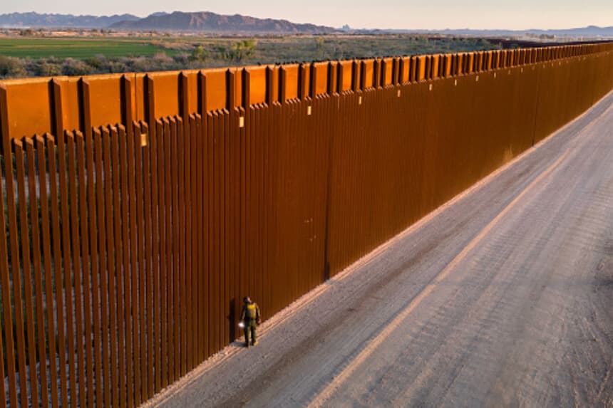 Panorámica aérea de un agente de la Patrulla Fronteriza de EE. UU. que busca huellas de migrantes junto a la valla en Yuma, Arizona, el 9 de marzo de 2024. La frontera entre Estados Unidos y México. (John Moore/Getty Images).