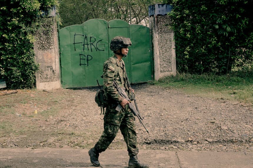 Un soldado colombiano pasa junto a una puerta metálica de garaje en la que se lee la inscripción «FARC-EP», siglas en español de las Fuerzas Armadas Revolucionarias de Colombia-Ejército del Pueblo, en Jamundi, departamento del Valle del Cauca, Colombia, el 27 de abril de 2026. (Joaquín SARMIENTO / AFP vía Getty Images)