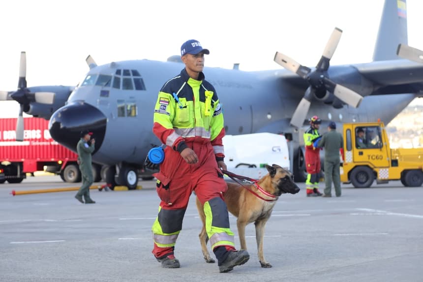 Un bombero camina con un perro preparándose para viajar a Venezuela este jueves desde la ciudad de Latacunga, Ecuador. (EFE/Diego Paredes)