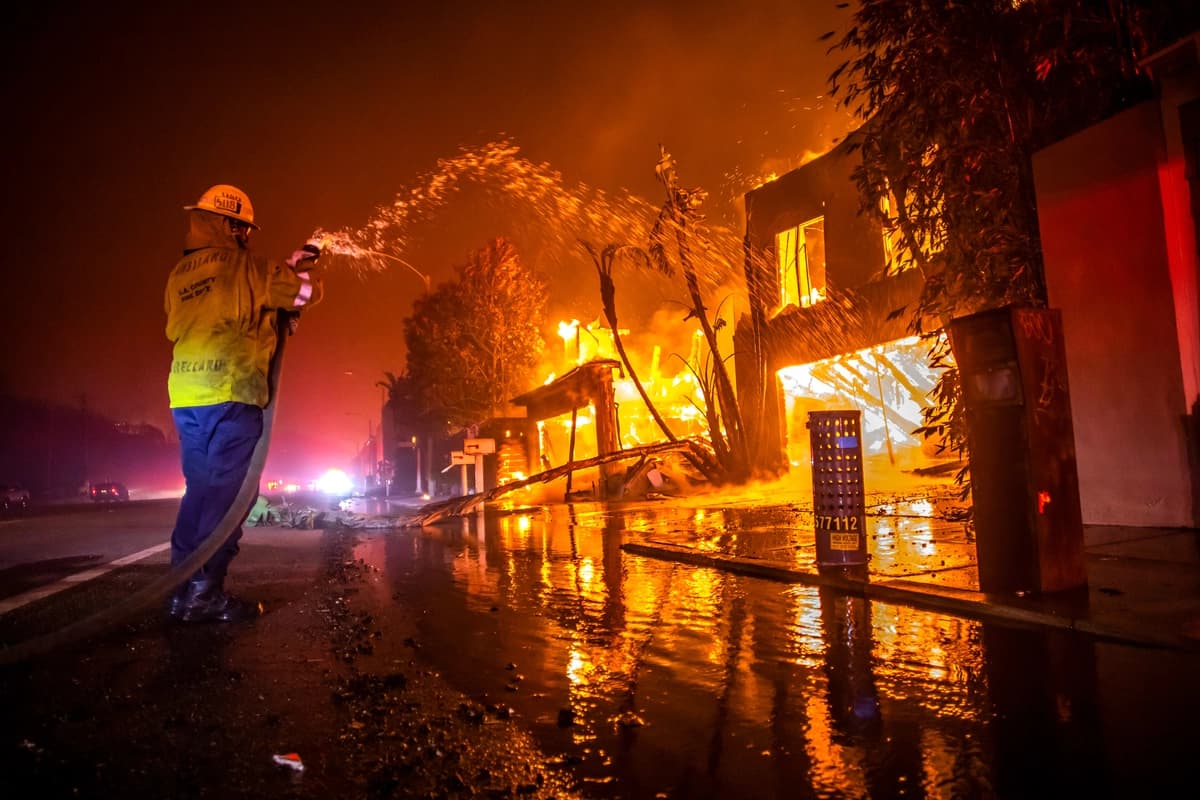 Un bombero lucha contra el incendio de Palisades mientras este arrasa viviendas en la Pacific Coast Highway durante una fuerte tormenta de viento en Los Ángeles el 8 de enero de 2025. El incendio forestal duró 24 días, causó la muerte de 12 residentes, obligó a miles de personas a evacuar sus hogares y dejó barrios enteros inhabitables. (Apu Gomes/Getty Images)