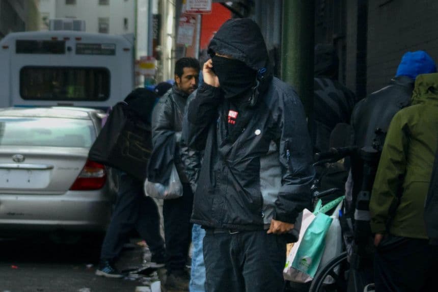 Un presunto narcotraficante se encuentra cerca de un grupo de drogadictos en San Francisco, California, el 23 de febrero de 2023. (John Fredricks/The Epoch Times)