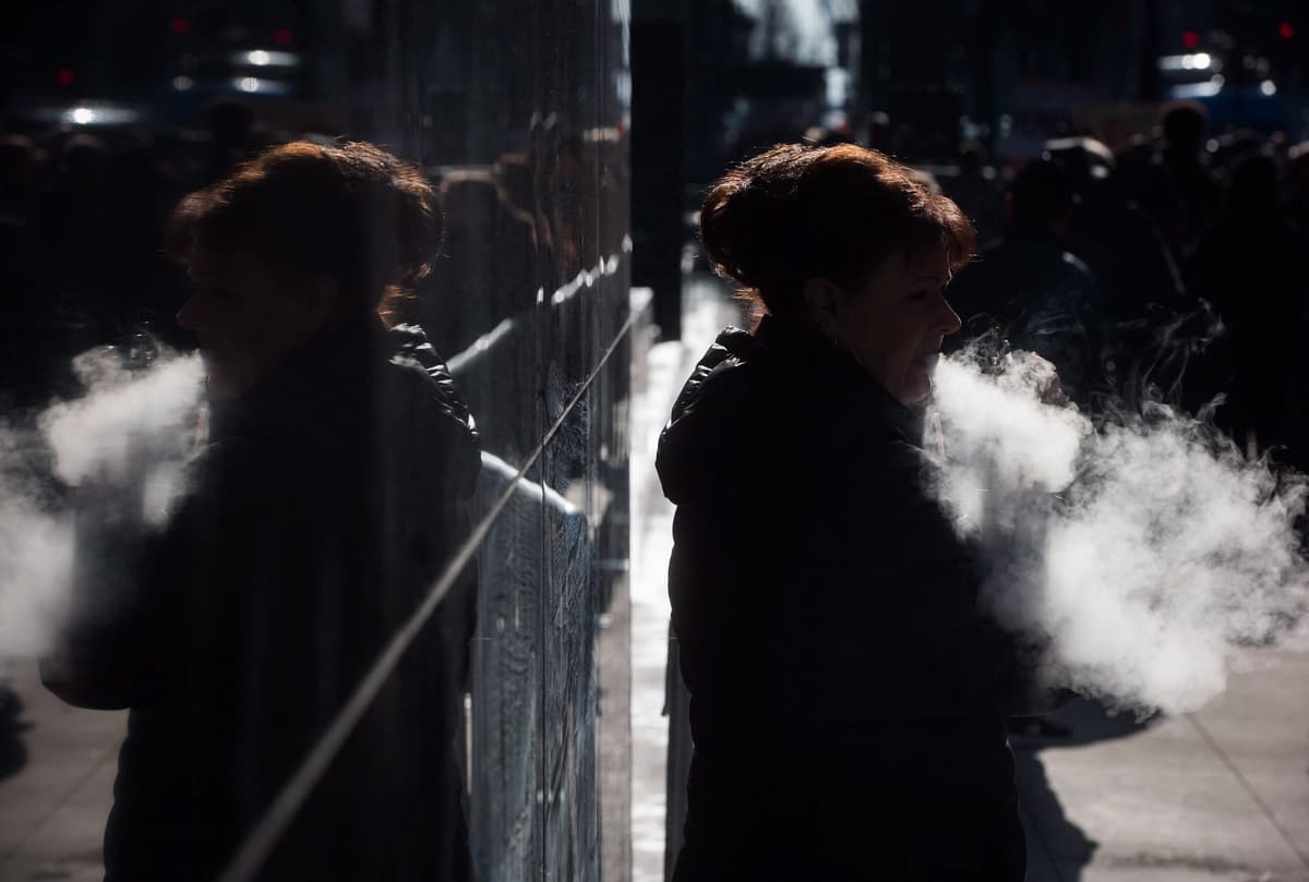 Una mujer exhala mientras usa un vaporizador frente a un edificio de oficinas en el centro de Vancouver el 28 de febrero de 2017. (The Canadian Press/Darryl Dyck).
