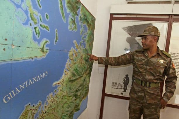 Un soldado cubano no identificado señala en un mapa el lugar donde se encuentran los campamentos de detención de talibanes dentro de la base estadounidense de Guantánamo, en Cuba, el 10 de septiembre de 2002.(ADALBERTO ROQUE/AFP vía Getty Images)