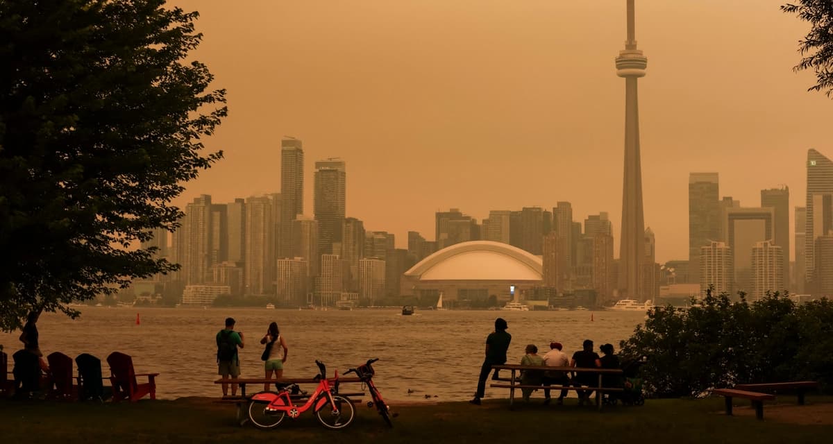 La gente contempla el horizonte del centro de la ciudad desde las Islas de Toronto, mientras los incendios forestales en Ontario provocan una mala calidad del aire sobre la ciudad, en Toronto, el 15 de julio de 2026. (Cole Burston / AFP vía Getty Images)
