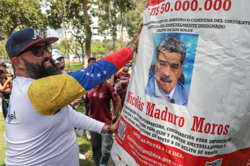 Un hombre pega un cartel con una recompensa de US$50 millones y la imagen de Nicolás Maduro cerca de la embajada de Venezuela en Lima, el 3 de enero de 2026, tras su captura por fuerzas estadounidenses. (Connie France / AFP vía Getty Images).