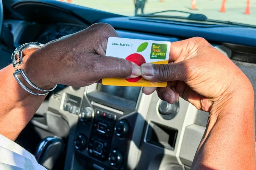 Una mujer sostiene una tarjeta que la identifica como beneficiaria de SNAP mientras espera para recibir suministros del Programa del Banco de Alimentos de Houston en el NRG Stadium de Houston, Texas, el 1 de noviembre de 2025. (Moisés Ávila/AFP vía Getty Images).