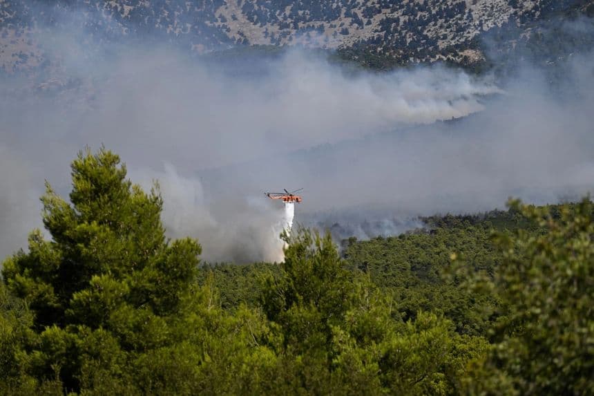 Un helicóptero de extinción de incendios arroja agua sobre un bosque lleno de humo durante un incendio forestal cerca de Porto Germeno, al noroeste de Atenas, Grecia, el 2 de agosto de 2026. (Foto de Michael Varaklas/AP)