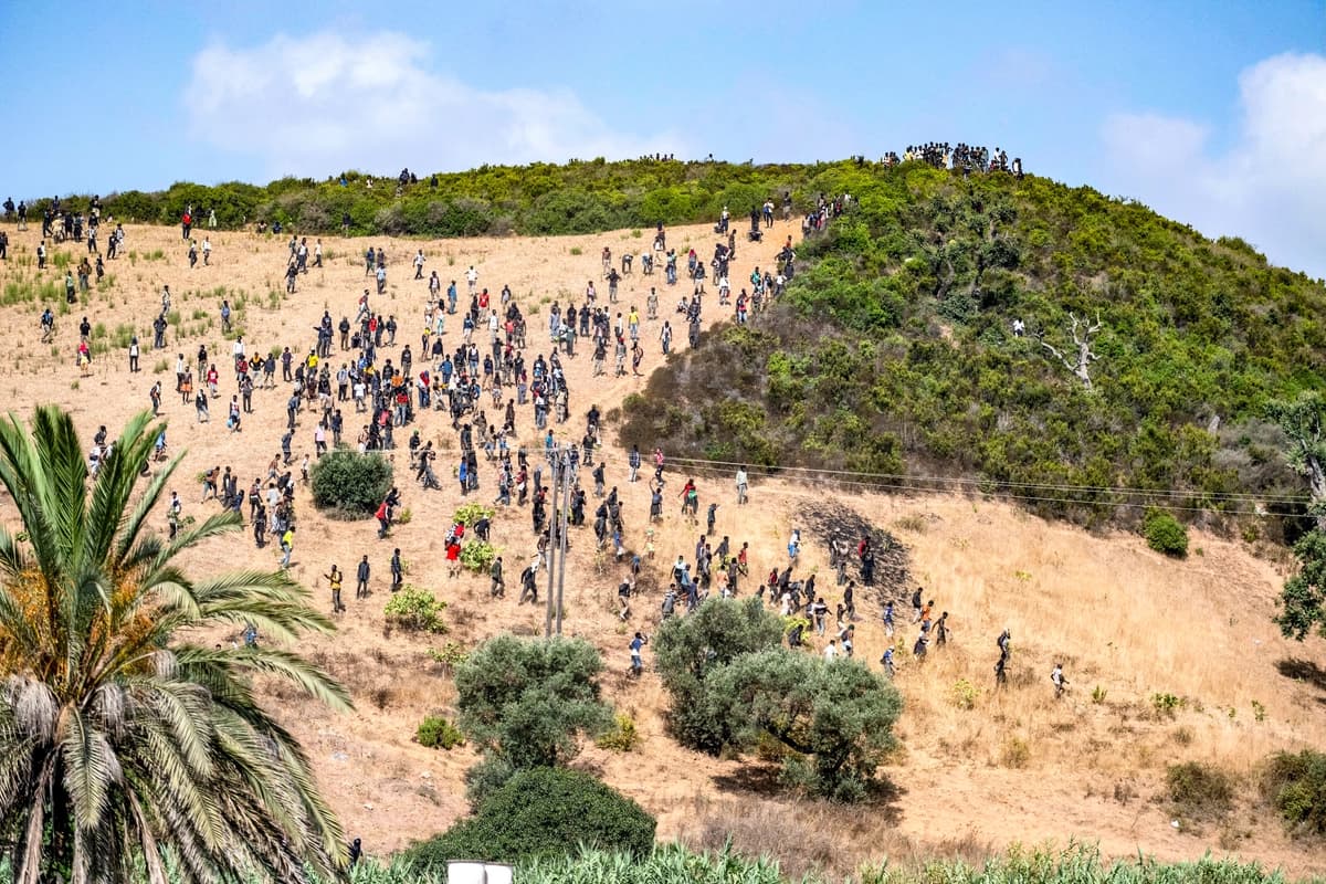Inmigrantes se congregan en una colina mientras intentan cruzar desde la ciudad fronteriza de Fnideq, en Marruecos, al enclave español de Ceuta, el 15 de agosto de 2026. (Foto AP).