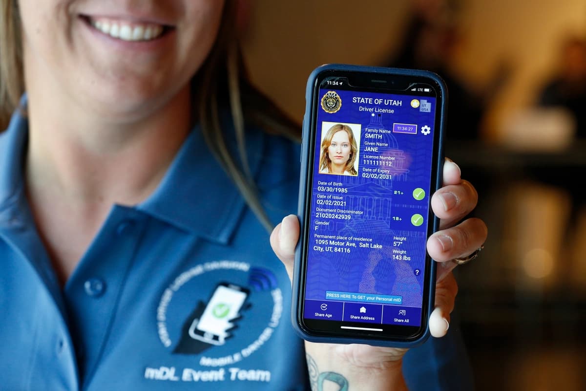 Un empleado del Departamento de Vehículos Motorizados de Utah muestra una muestra de una licencia de conducir digital en un teléfono celular en una tienda de comestibles Harmons en Salt Lake City, Utah, el 4 de agosto de 2021. (George Frey/Getty Images)