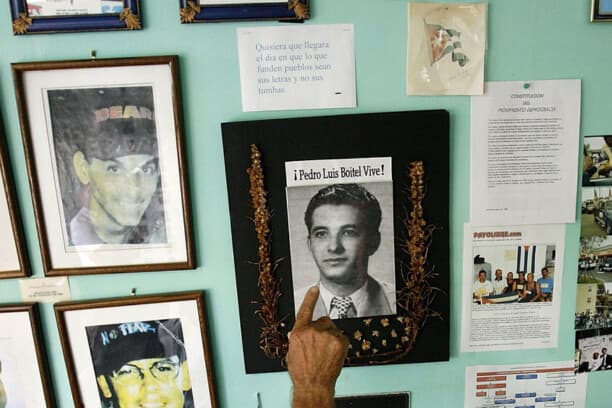 MIAMI - 2 DE AGOSTO: Voluntarios de la organización cubano-estadounidense por la democracia "Movimiento Democracia" observan fotografías de personas que han fallecido o han sido asesinadas por oponerse al gobierno de Castro en Cuba, en su oficina el 2 de agosto de 2006 en Miami, Florida. La fotografía del centro es de Pedro Luis Boitel, quien murió en huelga de hambre mientras se encontraba en prisión en Cuba en 1972. (Chip Somodevilla/Getty Images)
