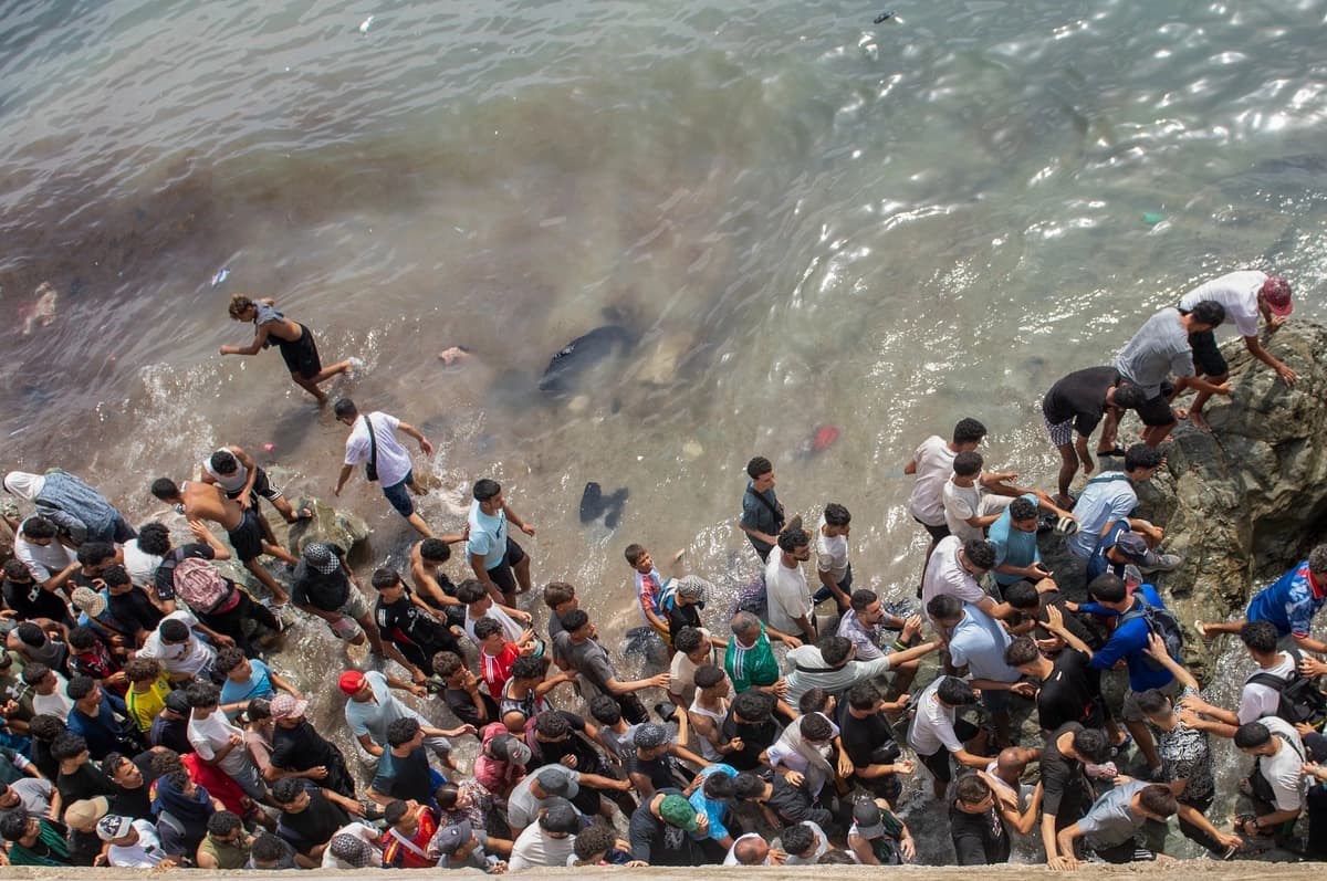 Migrantes caminan por una playa mientras intentan cruzar ilegalmente desde la ciudad marroquí de Fnideq, en el norte del país, hasta el enclave español de Ceuta, el 31 de julio de 2026. (Foto AP).