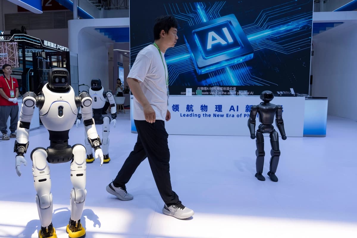 Un trabajador pasa junto a robots en la Exposición Internacional de la Cadena de Suministro de China en Beijing el 22 de junio de 2026. (Ng Han Guan/AP).