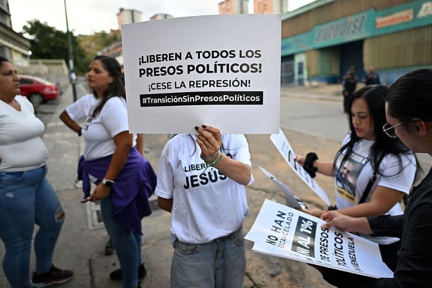 Un manifestante muestra un cartel en el que se lee en español: "¡Liberen a todos los presos políticos!", "¡Cese la represión!", durante una manifestación de familiares de presos políticos que exigían la liberación de sus seres queridos, cerca del famoso El Helicoide —una instalación y prisión propiedad del gobierno venezolano utilizada tanto para presos comunes como políticos del Servicio Bolivariano de Inteligencia Nacional (SEBIN)— en Caracas, el 9 de enero de 2026. (Juan BARRETO / AFP vía Getty Images)